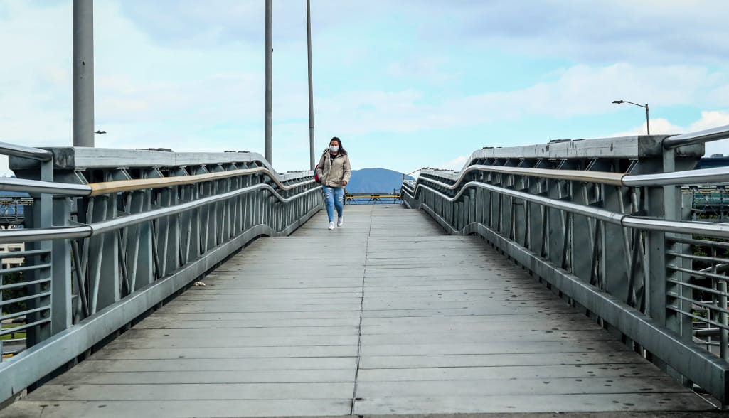 Fotografía de una persona caminando en un puente peatonal.d