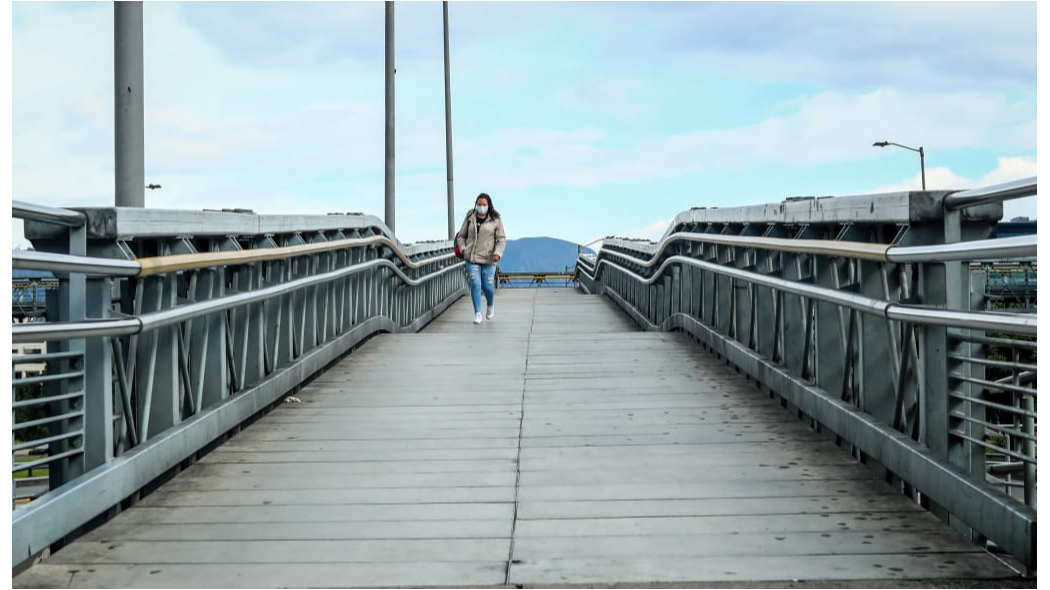 Fotografía de una persona caminando en un puente peatonal.