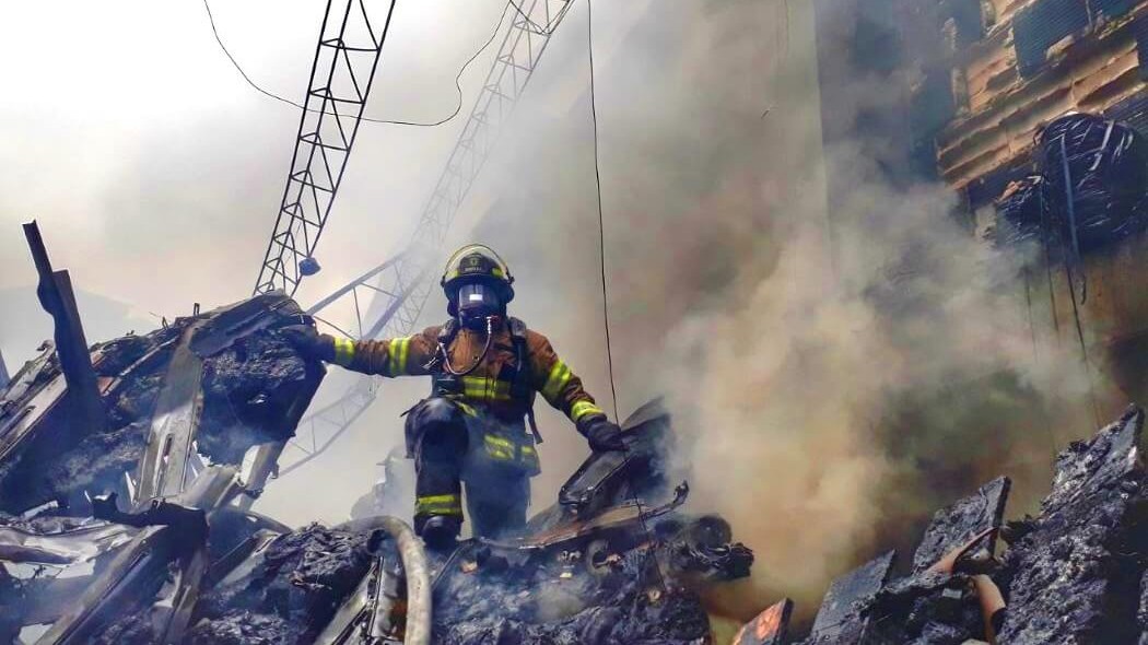 Imagen de un bombero saliendo del humo de un incendio.