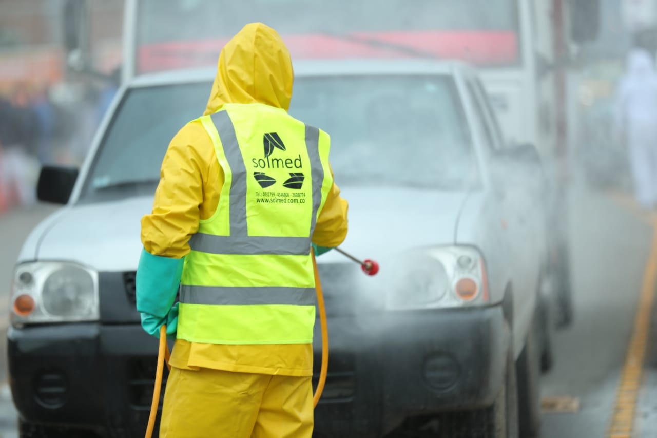 Persona rociando desinfectante sobre un carro.