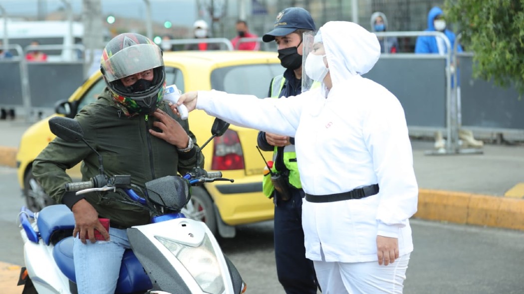 Funcionaria tomando la temperatura de un motociclista.