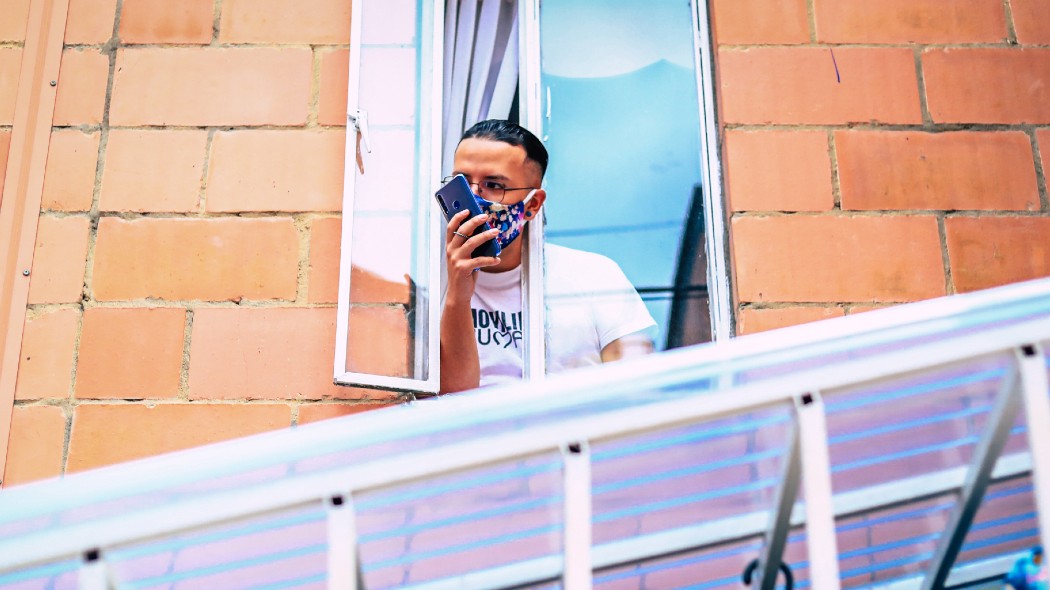 Persona en una ventana con el tapabocas puesto.