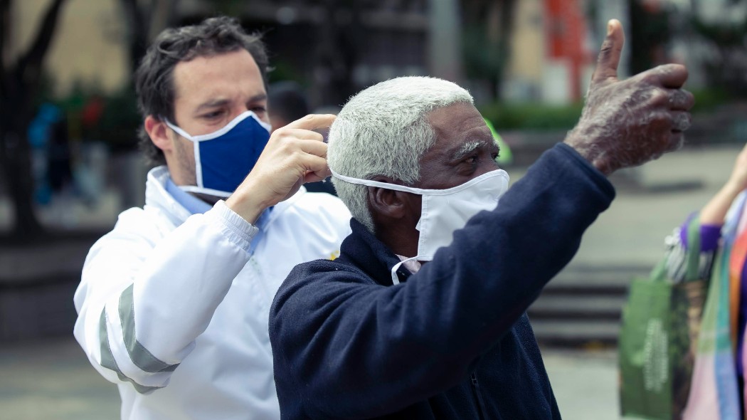 Secretario de Gobierno poniéndole mascarilla a un ciudadano.