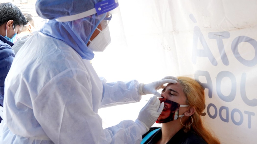 Trabajadora de la salud sacando la prueba de antígeno a una paciente.