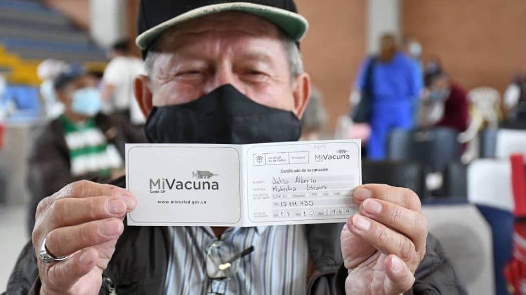 Imagen de un adulto mayor con su carnet de vacunación.