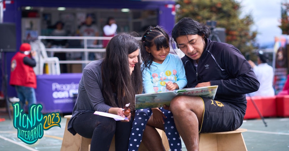 Padre y madre muestran un libro a su hija