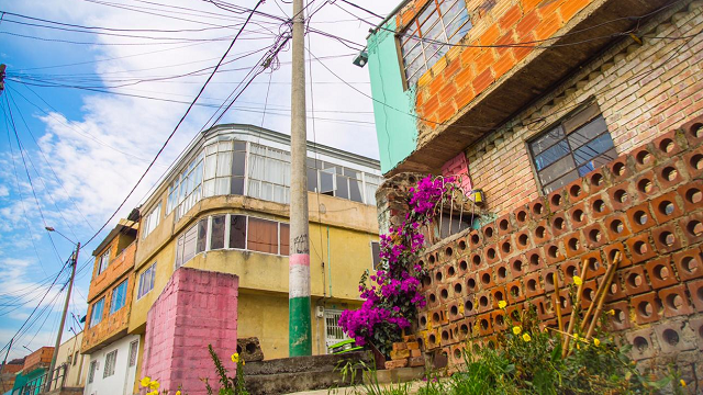 varias fachadas de casas, con varias buganvilias en sus balcones y entradas