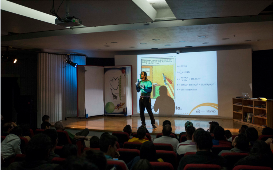 Un salón donde hay un hombre hablando y varias personas como publico observando