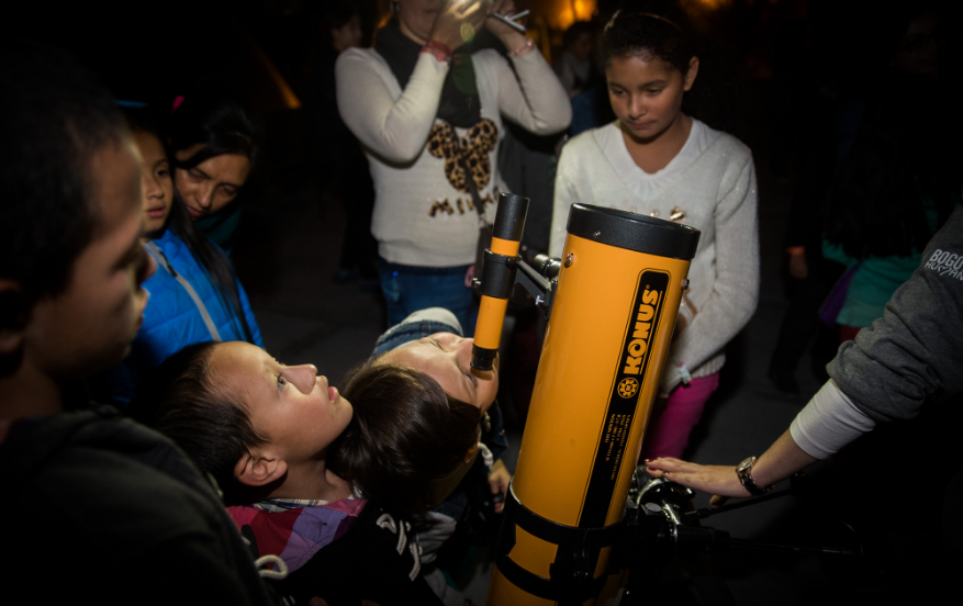 Personas reunidas alrededor de un telescopio