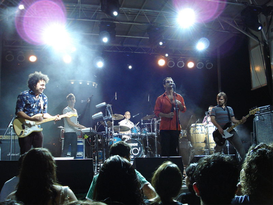 Tres integrantes de un grupo musical encima de un escenario.