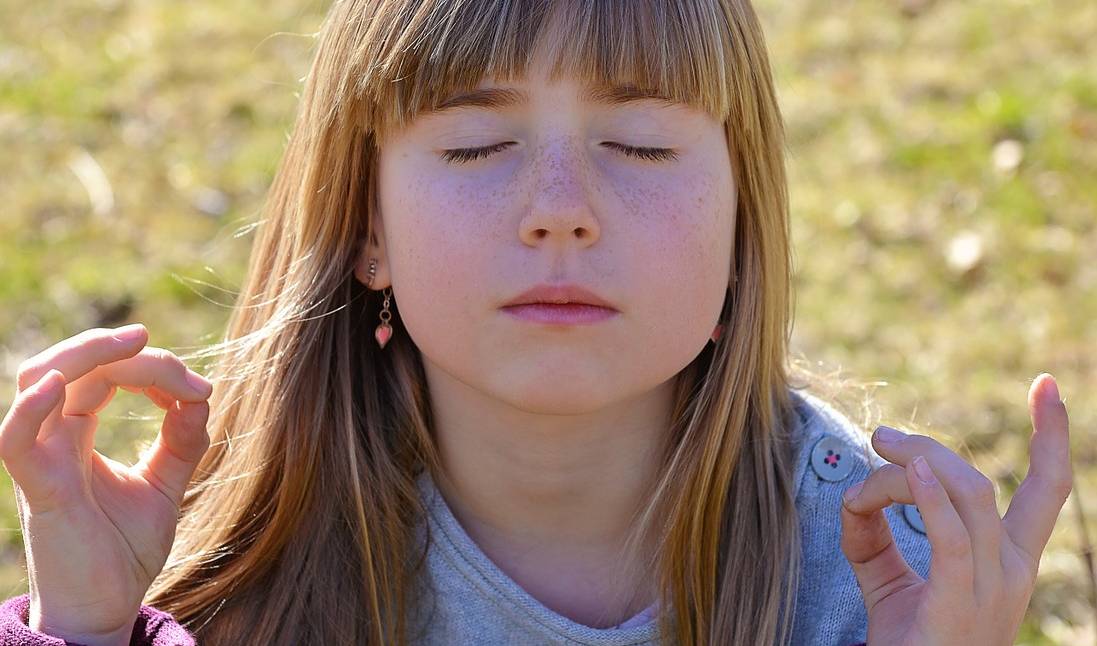 Niña haciendo una postura de calma y meditación.