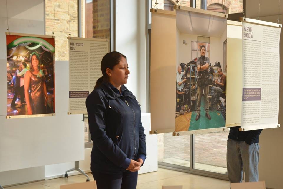 Una mujer de frente mirando un pendón con la historia del barrio Restrepo