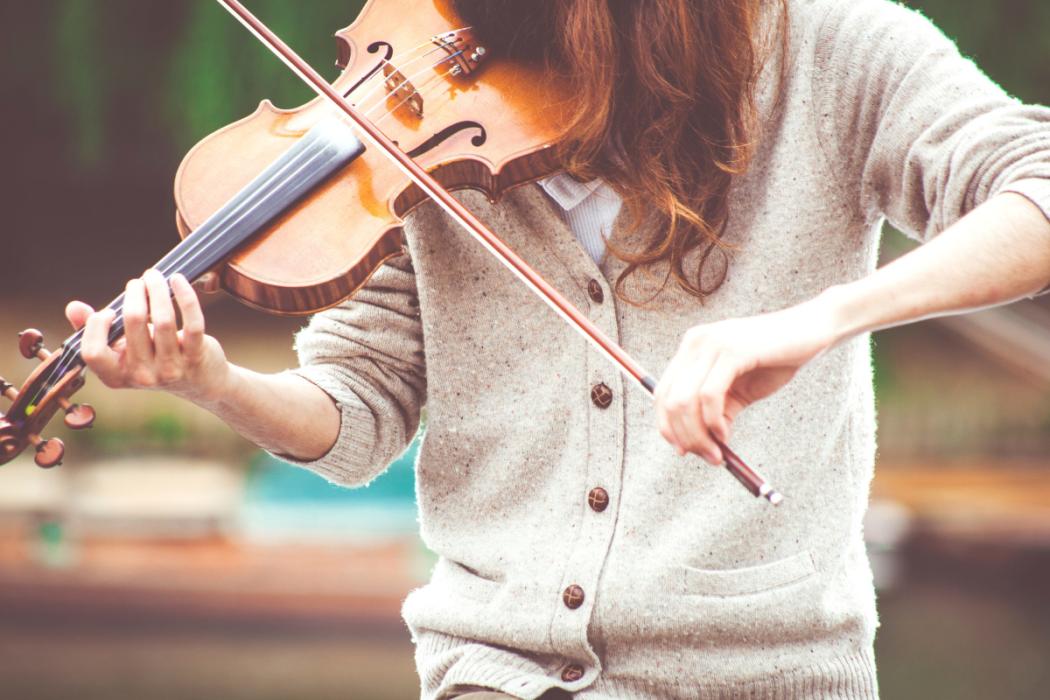 Mujer pelirroja joven interpretando el violín.