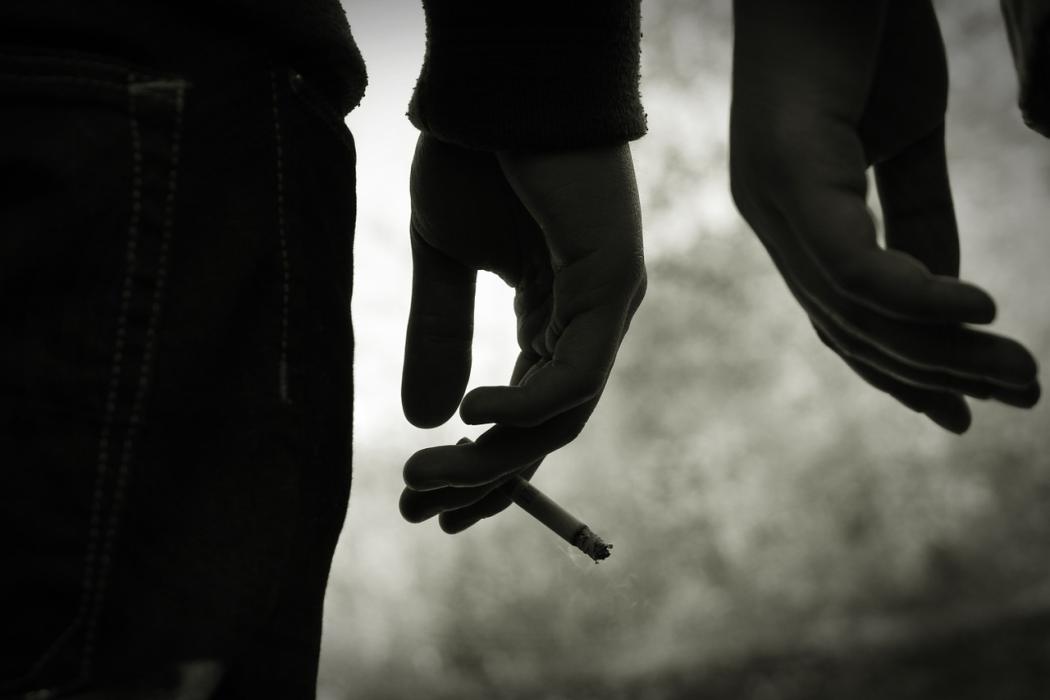 Silueta de la mano de un hombre sujetando un cigarillo