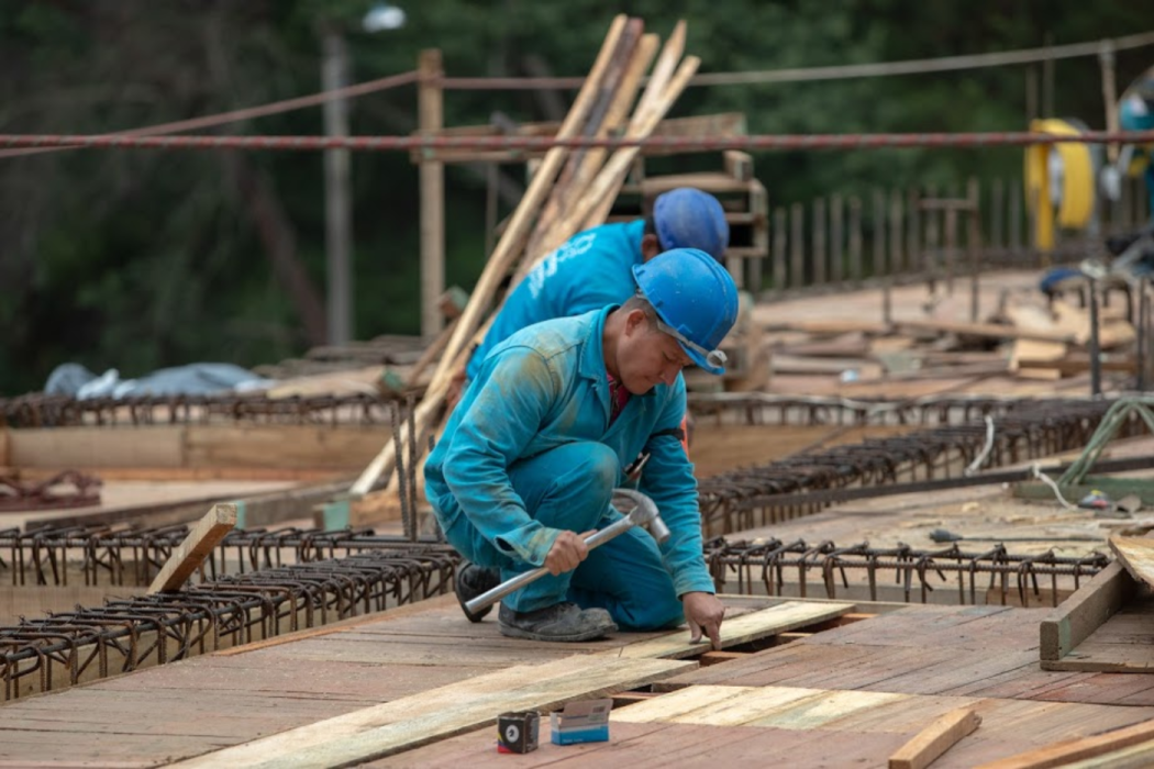 Un trabajador del Acueducto de Bogotá, martillando algunas tablas de madera 