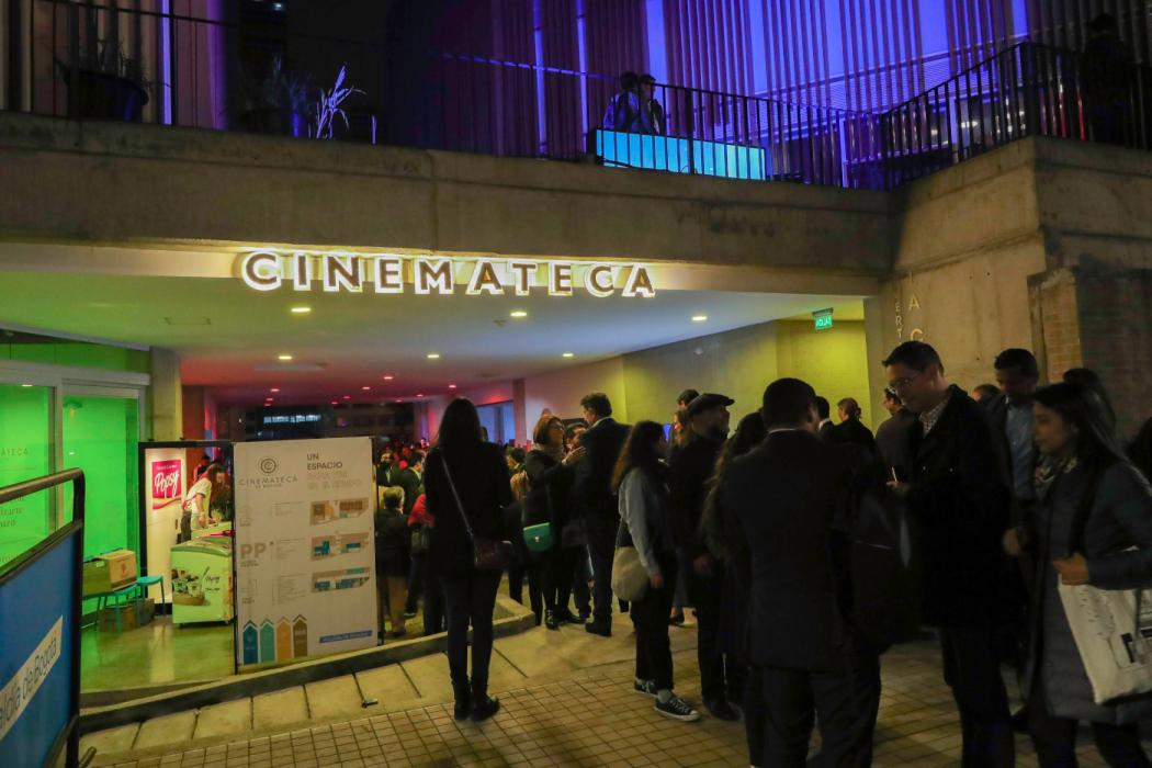 La fachada de la Cinemateca de Bogotá, de noche, con una fila de personas esperando para entrar