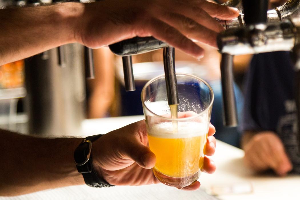 Una persona sirviendo un vaso de cerveza 