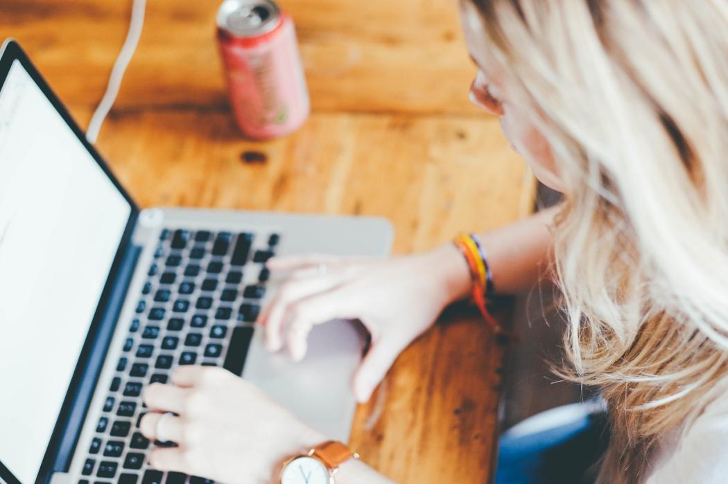 Una mujer rubia escribiendo en un portátil 