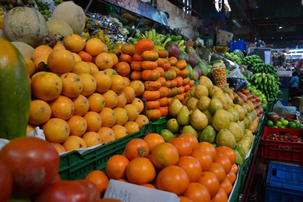 Una foto de varias frutas, granadillas, naranjas, mandarinas exhibidas en la plaza de mercado