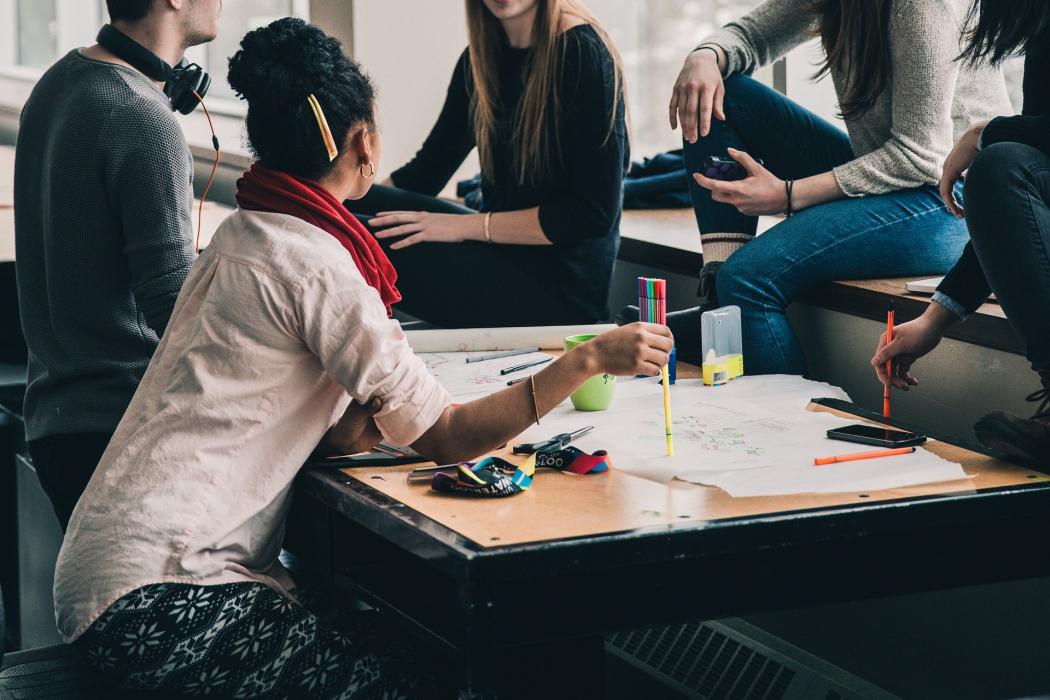 Varias personas reunidas al rededor de una mesa de trabajo 