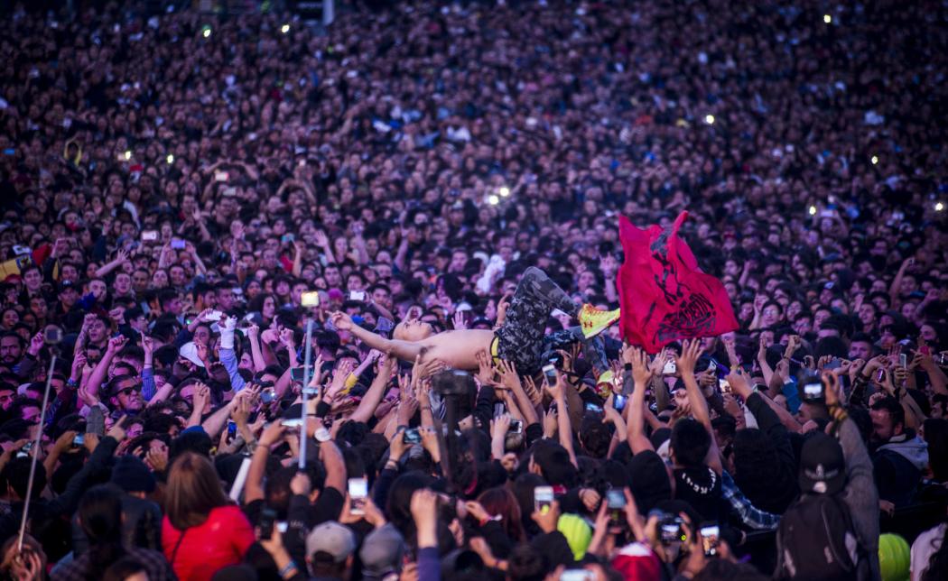 Varias personas gritando y alzando las manos en un concierto de Rock al Parque