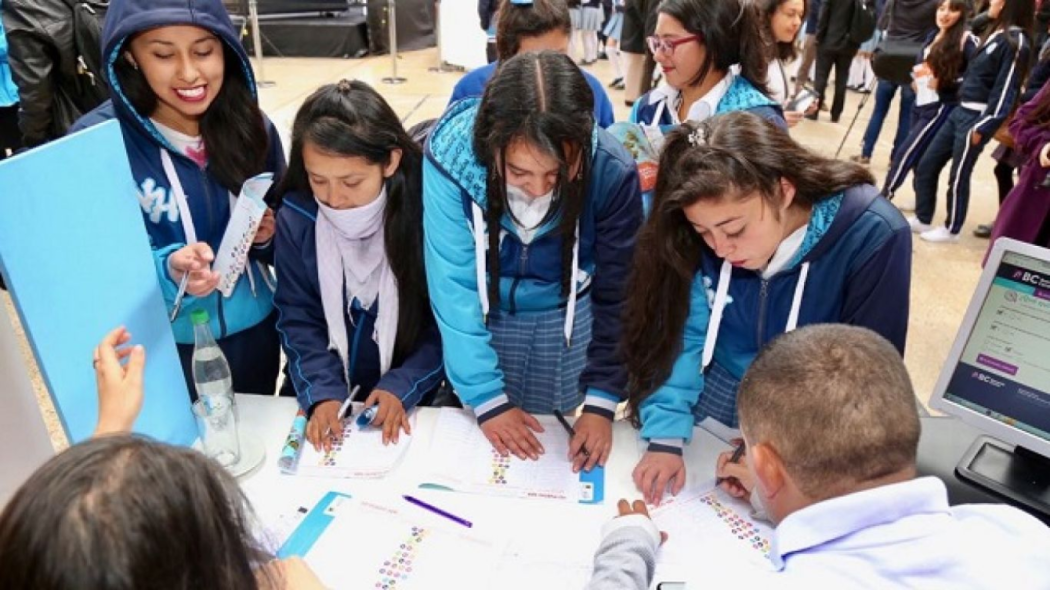 Un grupo de 5 jóvenes se registran en una mesa donde los atienden dos personas adultas 