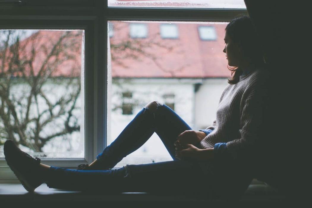 Imagen de una mujer sola mirando por la ventana