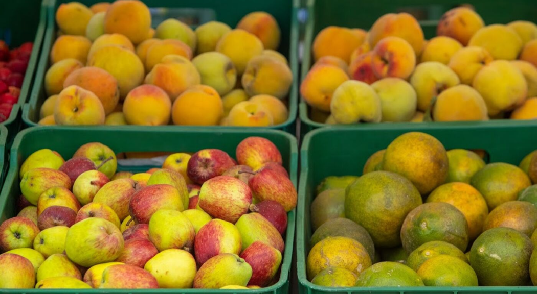 Primer plano de frutas exhibidas en canastas de color verde.