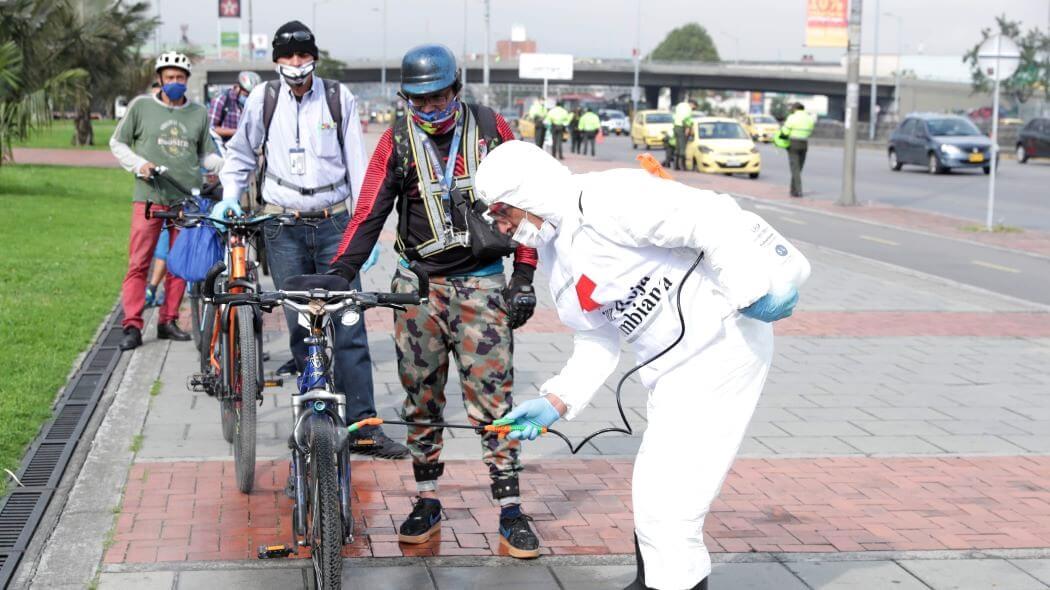 Imagen de un hombre de la Cruz Roja desinfectando ciclas de usuarios en la calle.