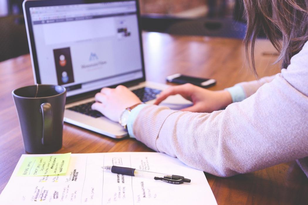 Mujer escribe en el teclado de un computador portátil 