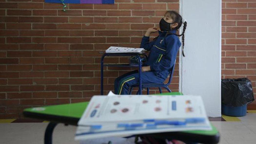 Niña de colegio tomando clase en su pupitre