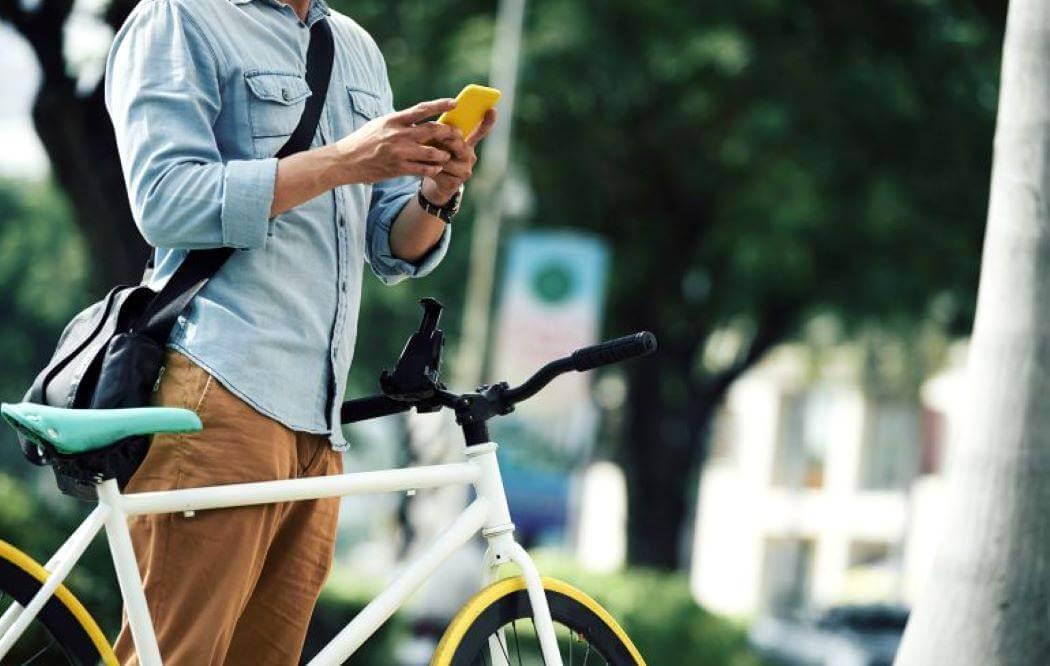 Imagen de una persona en bicicleta con su celular.