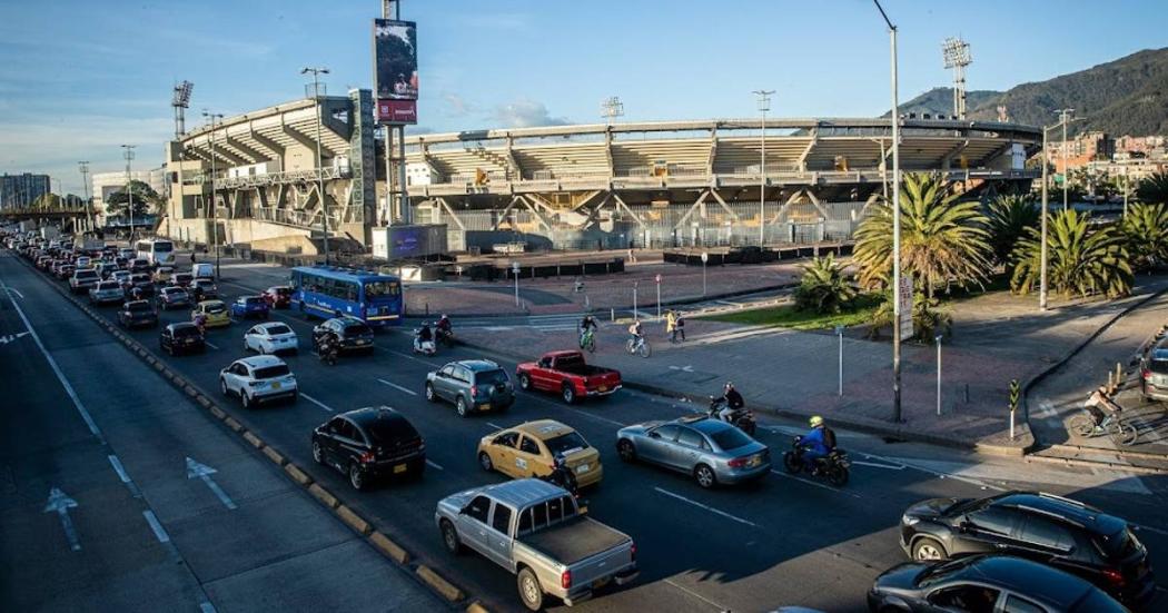 Carros en avenida principal al lado de un estadio