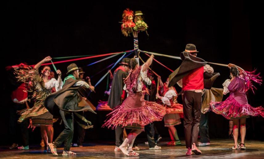 Varias personas bailando al rededor de un tubo, en una danza tradicional