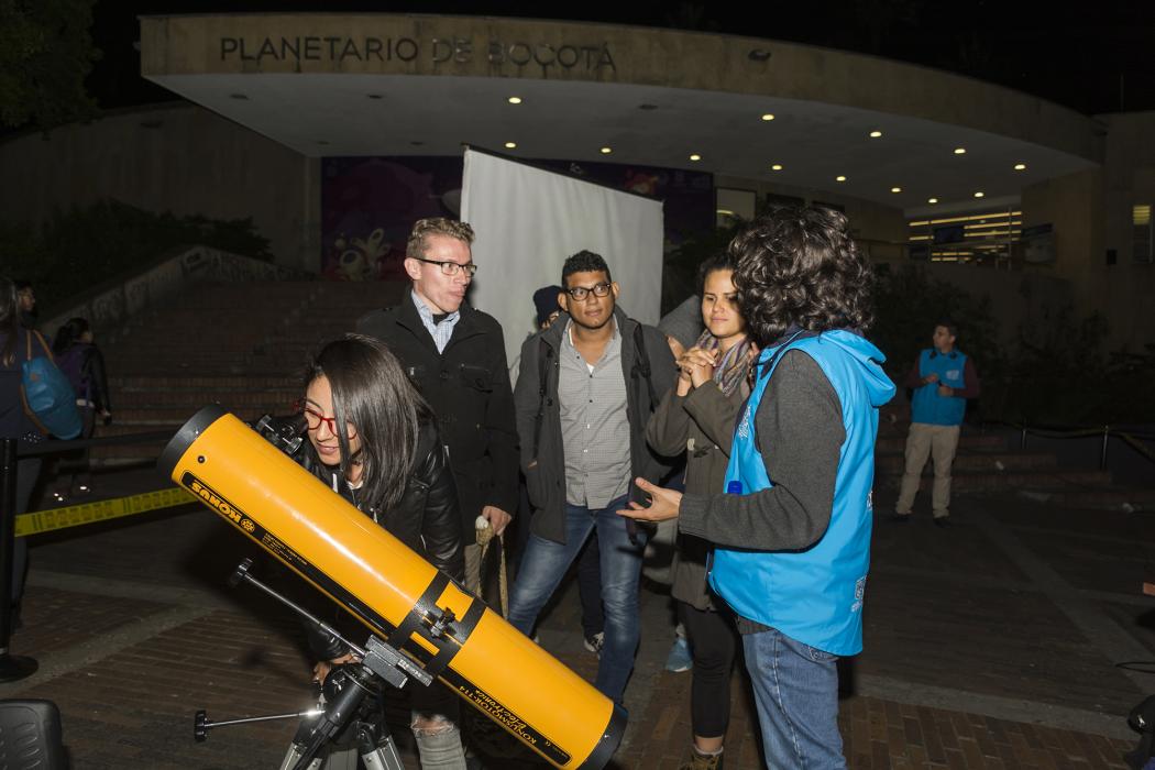 Varias personas alrededor de un telescopio 