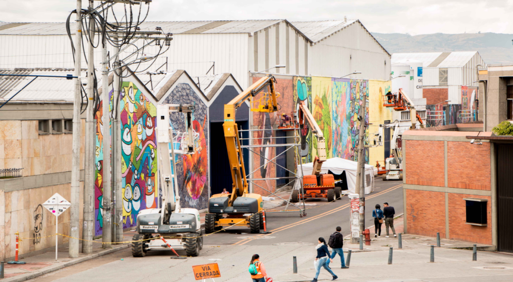 Varias edificios con graffitis, varias personas alrededor