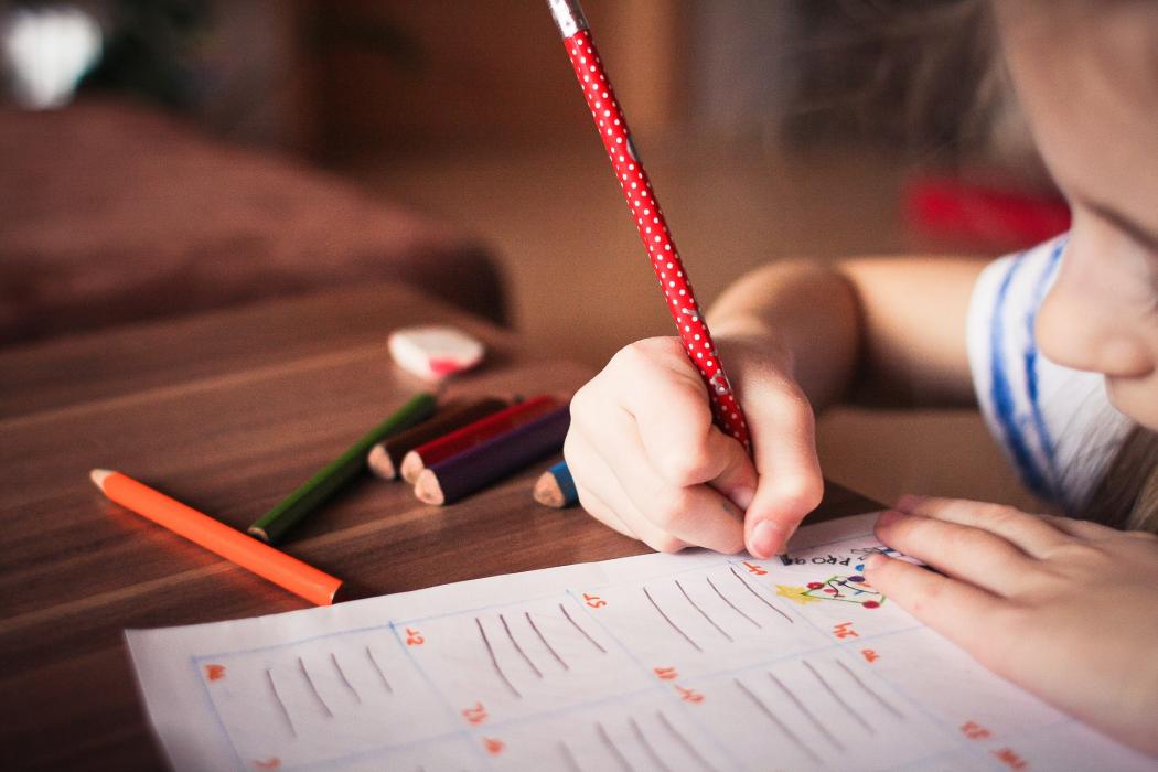 Un niña escribiendo en una hoja 