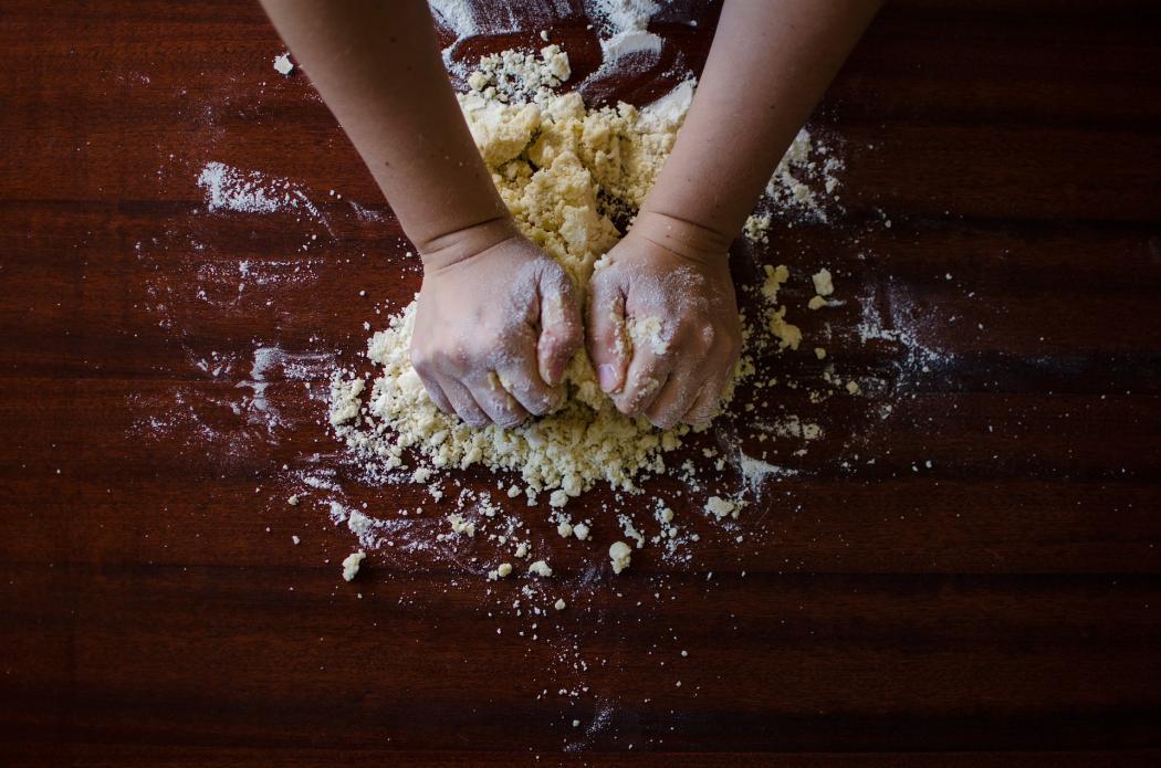 Dos manos amasando masa en una mesa