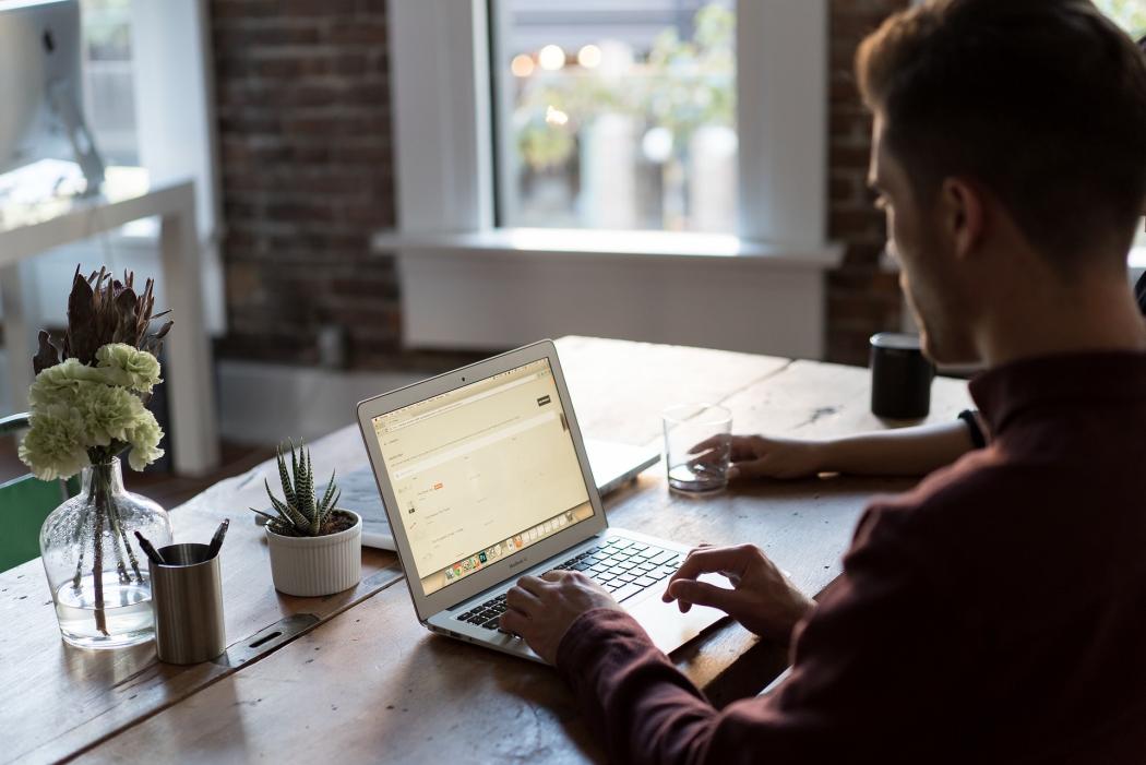 Un hombre de espaldas escribiendo en un portatil