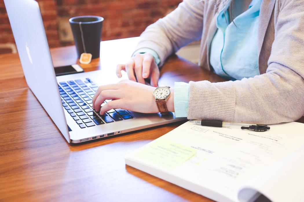 Un mujer escribiendo en un computador portatil 