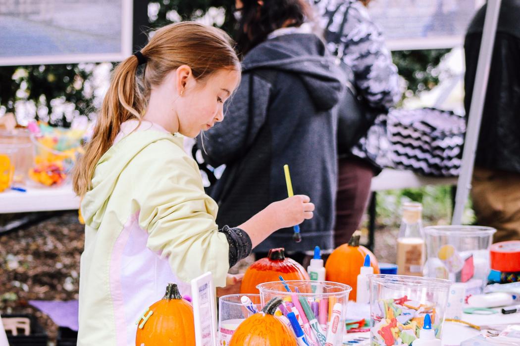 Una niña jugando y pintando unas calabazas de juguetes de color naranja