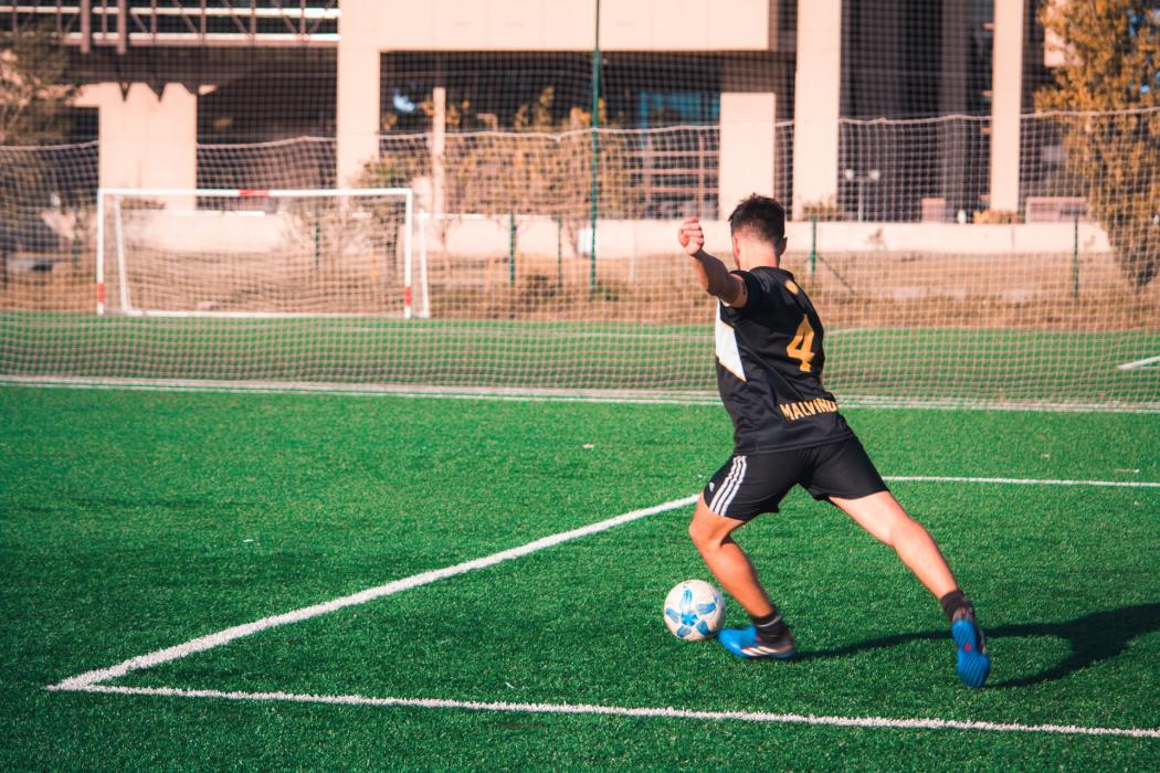 U hombre en una cancha de futbol a punto de patear un balón 