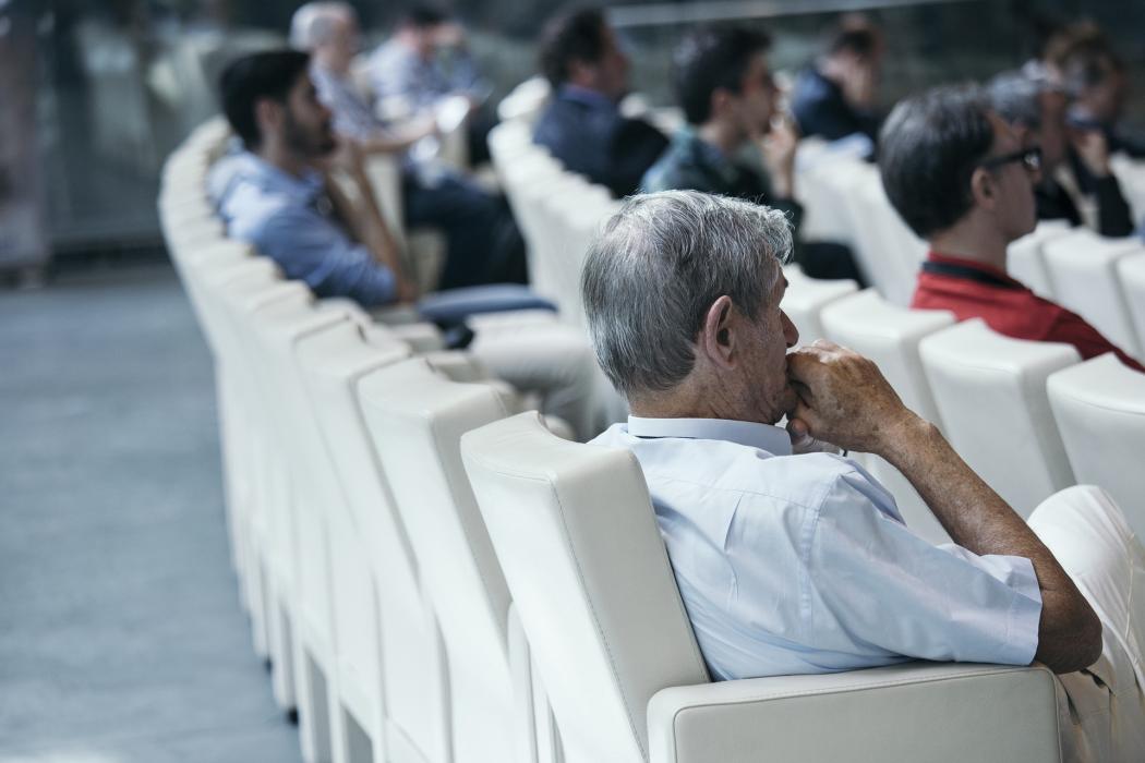 Una hilera de filas, hay varios hombres sentados escuchando el congreso