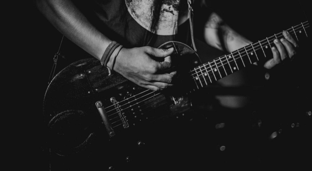 Primer plano de unas manos interpretando una guitarra eléctrica.