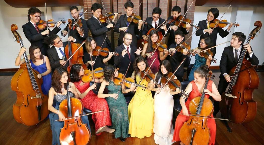 Un grupo de jóvenes interpretan instrumentos de cuerda.