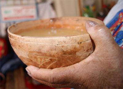 Primer plano de una totuma llena de chicha, una mano la sostiene.