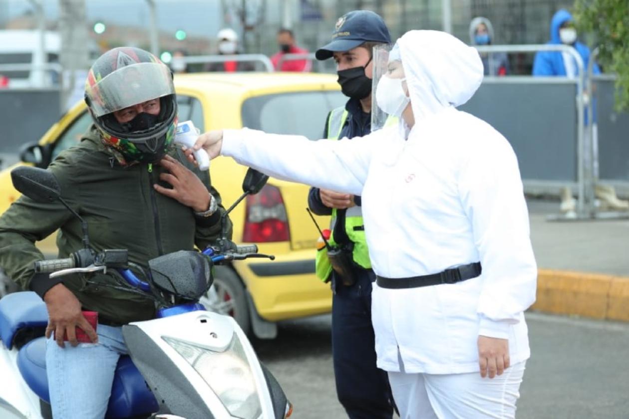 Funcionaria tomando la temperatura de un motociclista.