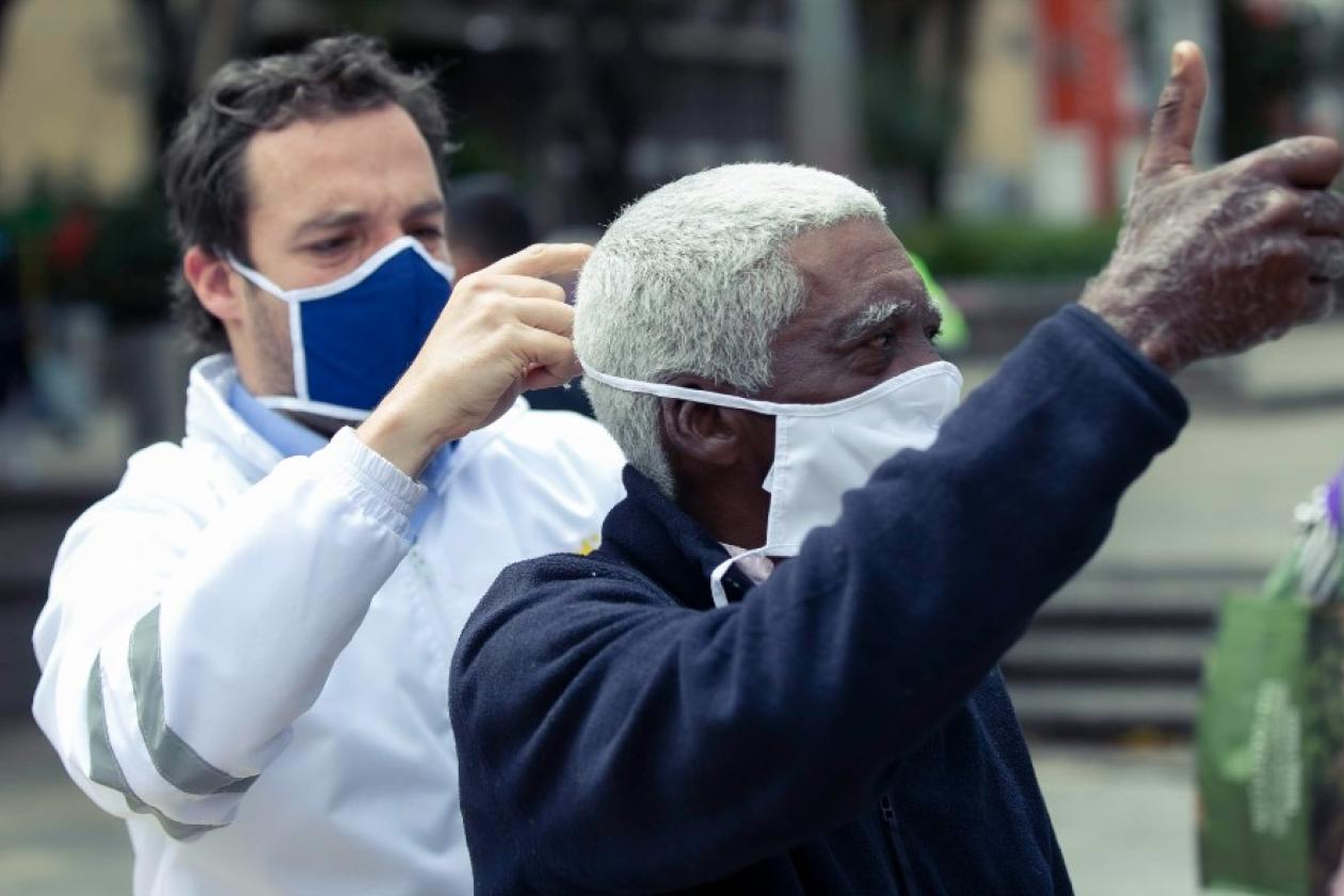 Secretario de Gobierno poniéndole mascarilla a un ciudadano.