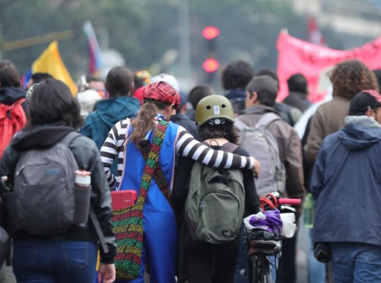 Jóvenes abrazándose y marchando de espaldas a la cámara