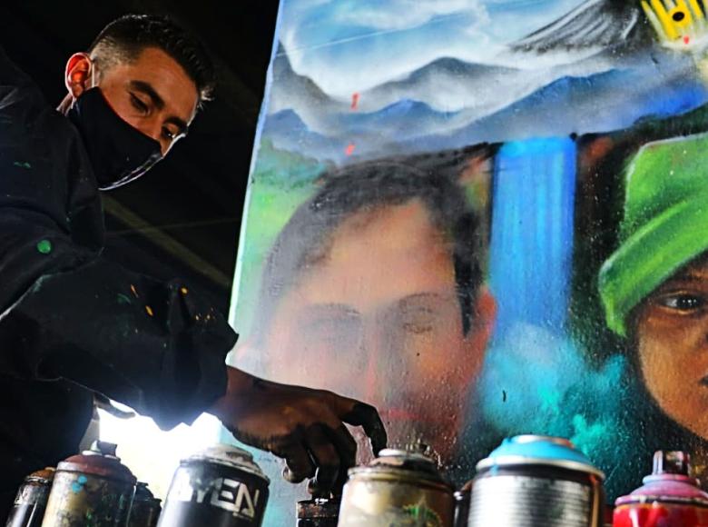 Jóvenes pintan rostros en los murales.